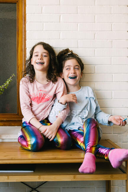 Dos hermanas sonrientes sacando una lengua azul después de comer un chicle azul - foto de stock