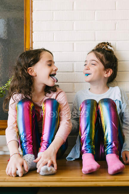 Deux sœurs souriantes sortant une langue bleue après avoir mangé une gomme à bulles bleue — Photo de stock