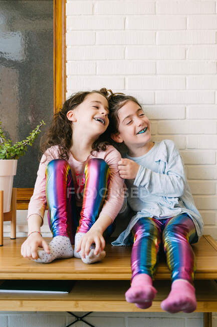 Dos hermanas sonrientes sacando una lengua azul después de comer un chicle azul - foto de stock