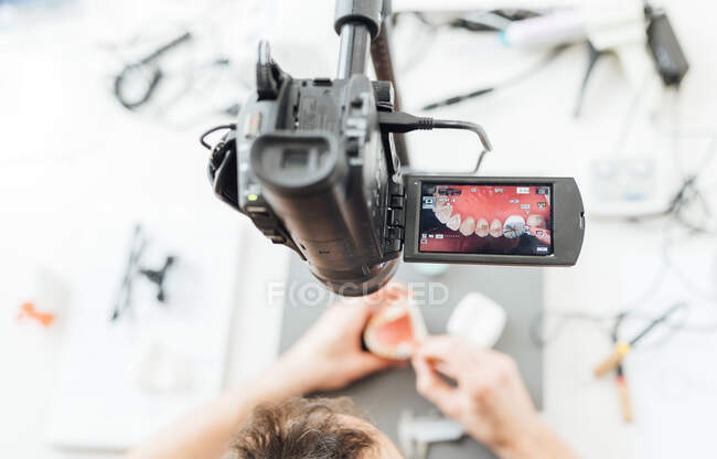 El profesor de odontología que trabaja la dentadura postiza con cámara de vídeo - foto de stock