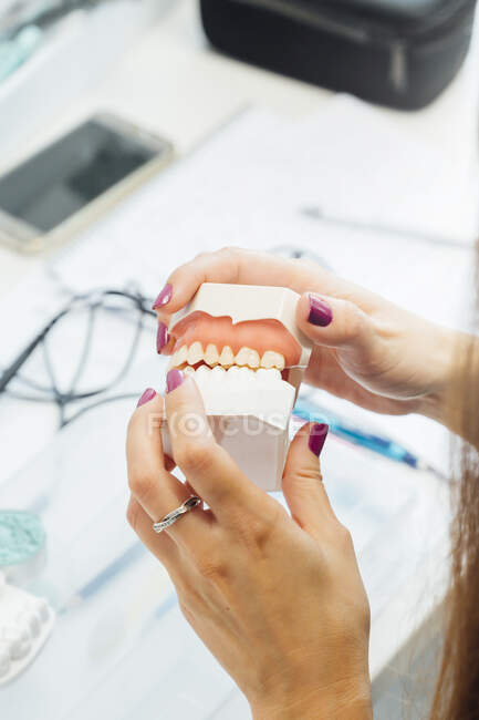 Von oben eine Studentin, die während des Zahnarztunterrichts am Tisch sitzt und eine Prothese hält — Stockfoto
