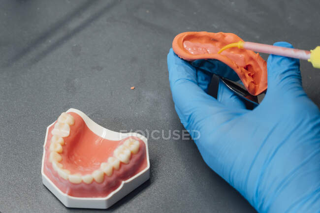 Зверху ззаду чоловічий ортодонт використовує професійне обладнання під час роботи з зубним відливом у сучасній лабораторії — стокове фото