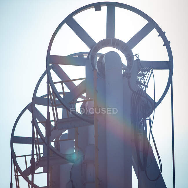 From below of metal wheels and belts of loading arms of modern petroleum machinery on background of blue sky — Stock Photo