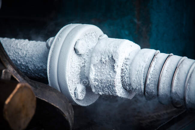 Closeup view of cooling pipe transferring liquid nitrogen surrounded by clouds of vapor on plant — Stock Photo