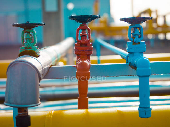 Row of colored metal faucets with valves and pipes transferring hot and cold water on plant — Stock Photo