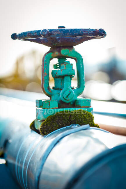 Fila de grifos de metal de color con válvulas y tuberías que transfieren agua fría y caliente en la planta - foto de stock