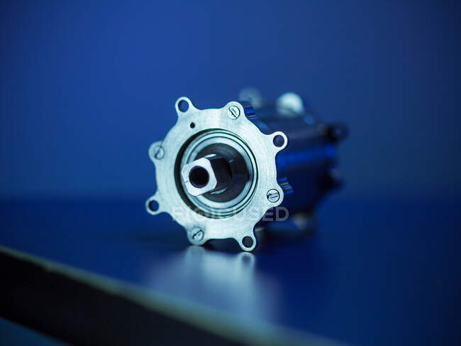 Elemento de mecanismo brillante con rodamiento de bolas de acero colocado sobre fondo azul en el taller - foto de stock