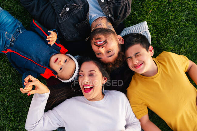 Familia feliz con un niño mintiendo sobre hierba verde - foto de stock