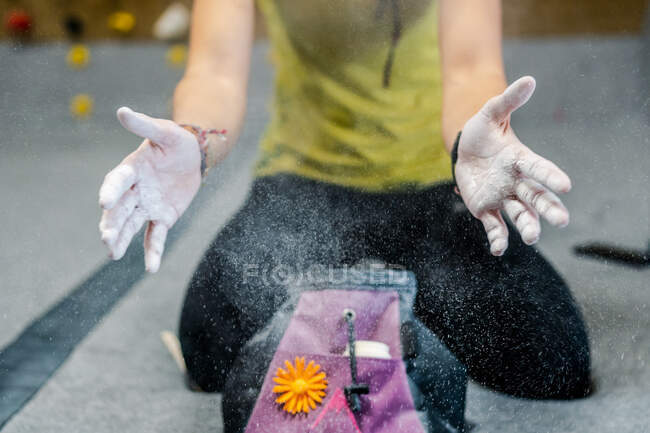Crop mani di donna sportiva senza volto in abbigliamento attivo seduto sul pavimento mentre ottenere talco in polvere in tutta la palestra moderna — Foto stock