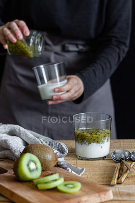 Schnittwunde an Frau in Schürze bei der Zubereitung von Joghurt mit frischem Kiwi-Püree — Stockfoto