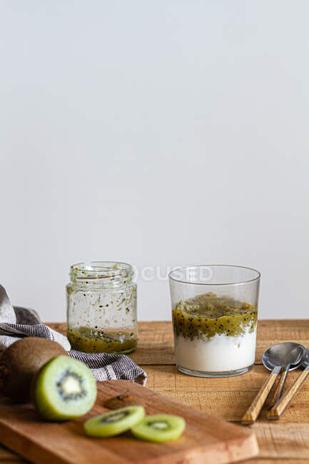 Vaso de sabroso batido casero saludable con yogur y kiwi fresco colocado sobre una mesa de madera - foto de stock