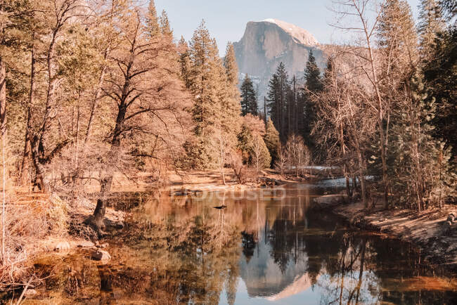 Falésias de granito sobre lago cercado por árvores de coníferas no Parque Nacional de Yosemite, na Califórnia — Fotografia de Stock