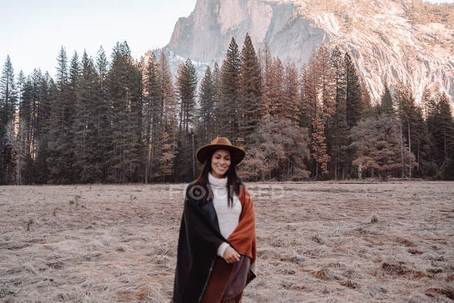 Щаслива розслаблена дівчина - мандрівник у стильному одязі, що сидить на кам 