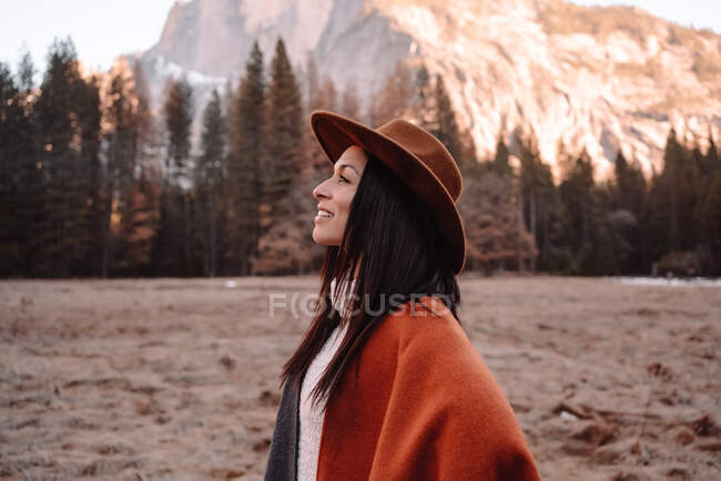 Щаслива розслаблена дівчина - мандрівник у стильному одязі, що сидить на кам 