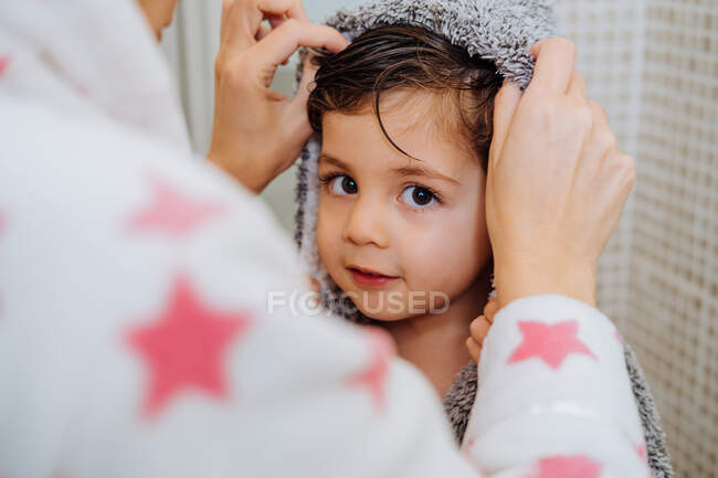 Cortada mulher irreconhecível com criança em roupão de banho depois de tomar banho e olhar para a câmera — Fotografia de Stock