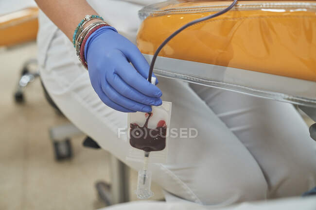 Crop especialista médico fêmea em luvas de látex realizando injeção com seringa para paciente anônimo durante procedimento de transfusão de sangue no hospital — Fotografia de Stock