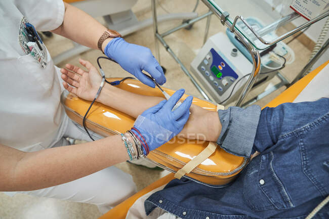 Самка - медик у латексних рукавичках впорскує шприц анонімному пацієнту під час переливання крові у лікарні. — стокове фото