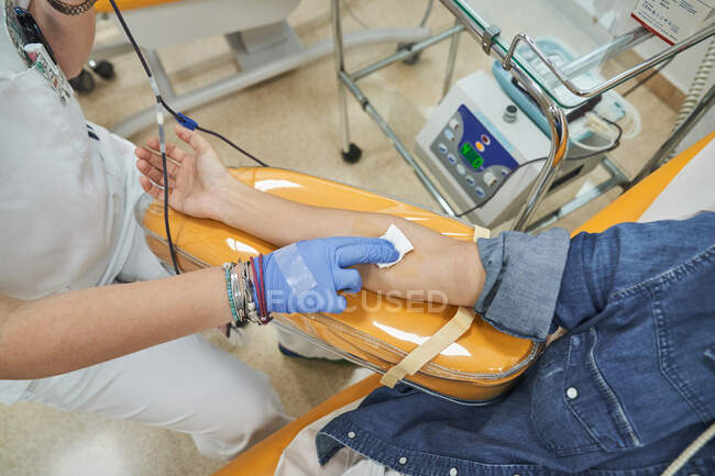 Cultivez une femme médecin spécialiste en gants de latex effectuant l'injection avec une seringue à un patient anonyme pendant la procédure de transfusion sanguine à l'hôpital — Photo de stock