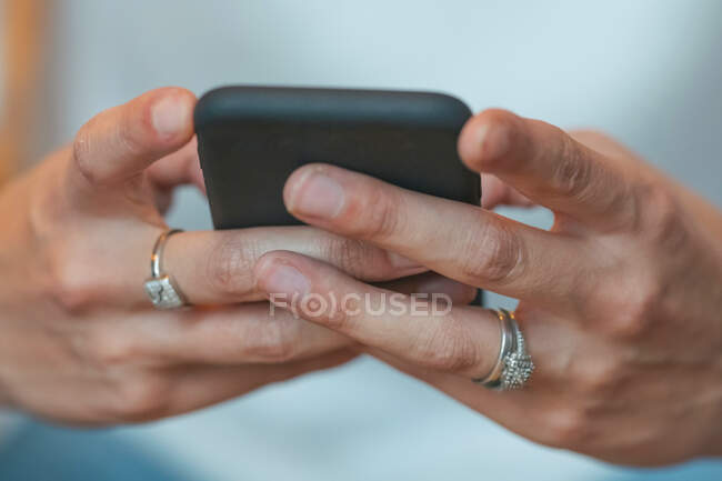 Low angle of crop female in white casual clothes and engagement rings interacting with smartphone — Stock Photo