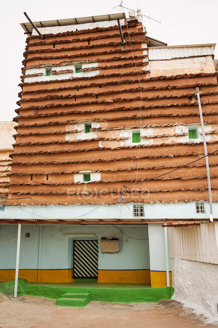 Das Äußere eines Wohnhauses mit traditionellen Ornamenten an der Fassade befindet sich in der Nähe entfernte Person am grauen Tag auf der Stadtstraße — Stockfoto