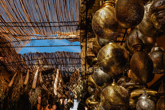 Bajo ángulo de bazar local marroquí con lámparas colgantes tradicionales y plantas secas en venta - foto de stock