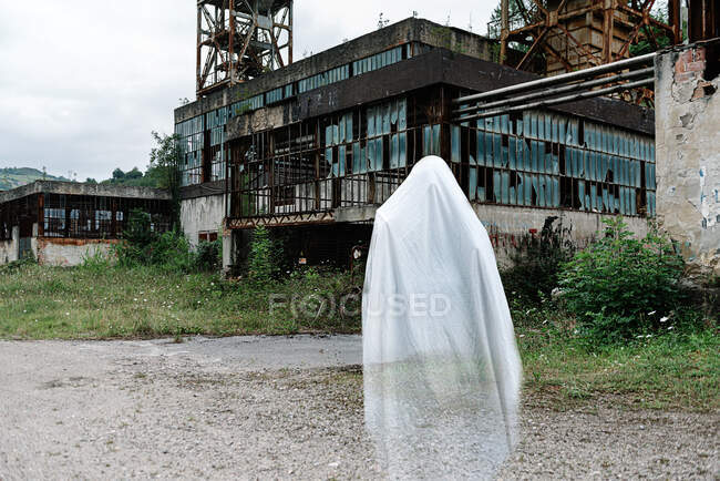 Transparent ghost near old abandoned mine building with rusty metal constructions and shabby walls — Stock Photo
