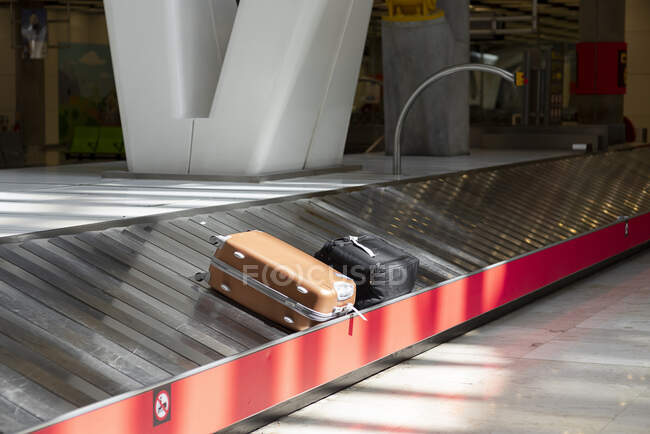 Correia transportadora de bagagem de metal com malas perto do botão de emergência vermelho no terminal do aeroporto vazio — Fotografia de Stock