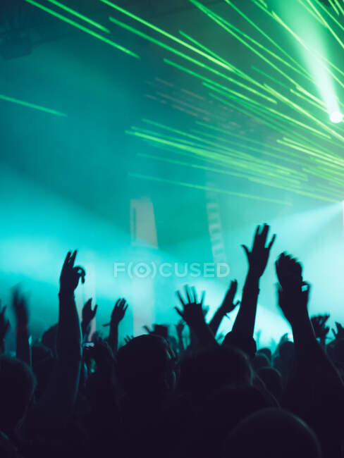 Vue arrière silhouettes de personnes contre éclairées avec des lumières scène pendant la performance musicale — Photo de stock