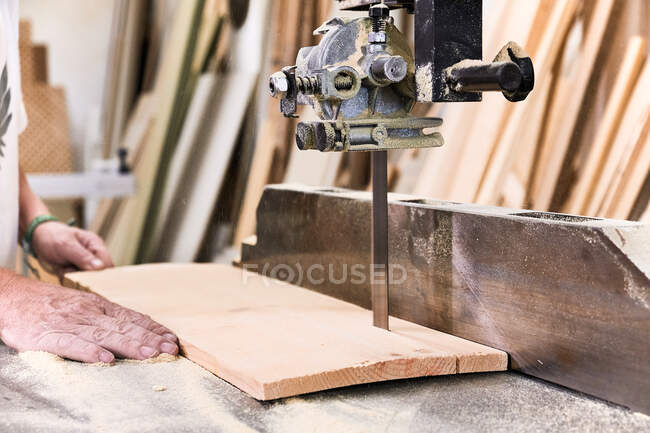Male woodworker in casual clothes focusing and cutting lumber using special electric machine while working in light modern workshop — Stock Photo