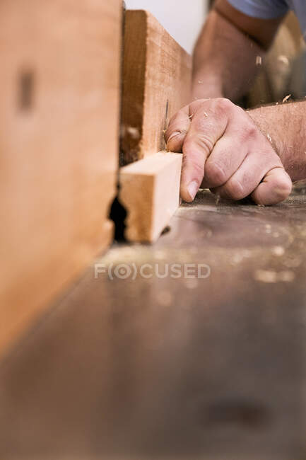 Bajo ángulo de primer plano irreconocible carpintería maestro fresado de madera utilizando la máquina eléctrica moderna en la luz taller contemporáneo - foto de stock