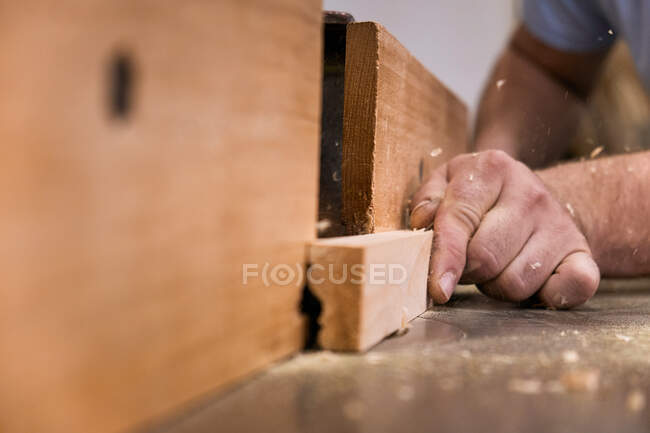 Low angle of closeup unrecognizable carpentry master milling timber using modern electric machine in light contemporary workshop — Stock Photo