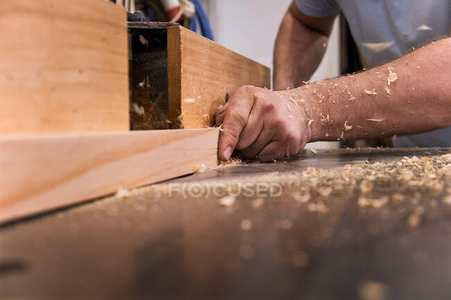 Baixo ângulo de closeup irreconhecível carpintaria mestre moagem de madeira usando máquina elétrica moderna na oficina contemporânea luz — Fotografia de Stock