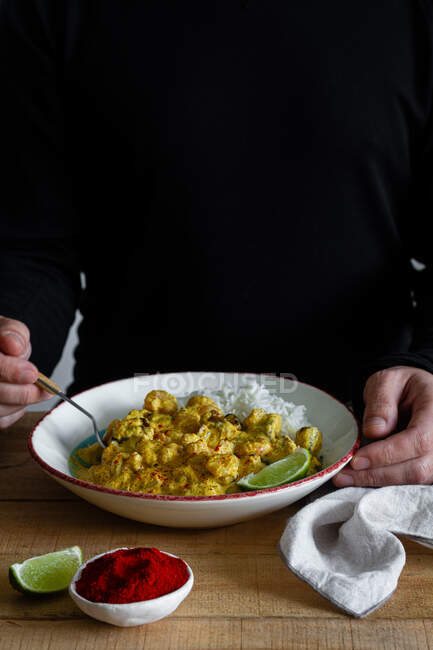 Обрезанный кадр человека с порцией креветочного карри с рисом — стоковое фото