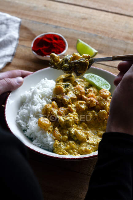 Tiro recortado del hombre con porción de gambas al curry con arroz - foto de stock