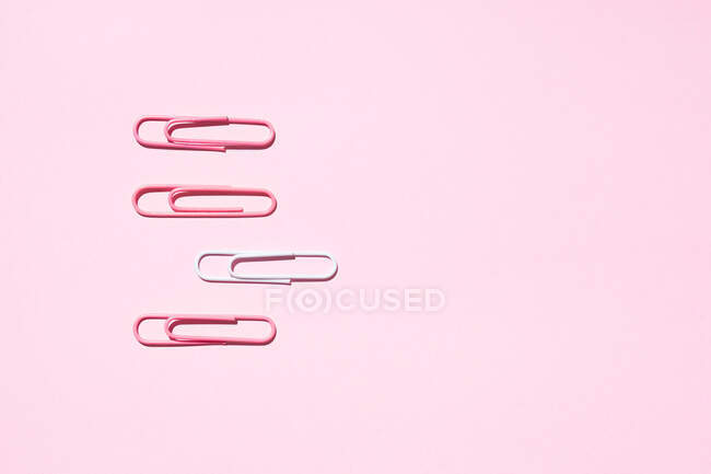 Draufsicht auf weiße und rosa Büroklammern auf buntem Hintergrund, die das Konzept der Einzigartigkeit zeigen — Stockfoto