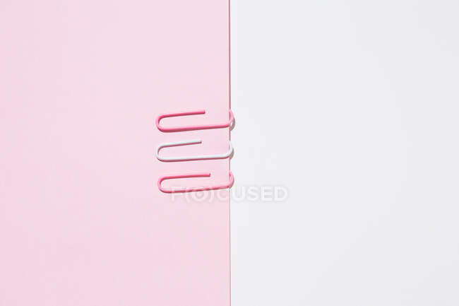 Vista superior de clips blancos y rosados dispuestos sobre un fondo colorido que muestra el concepto de singularidad - foto de stock