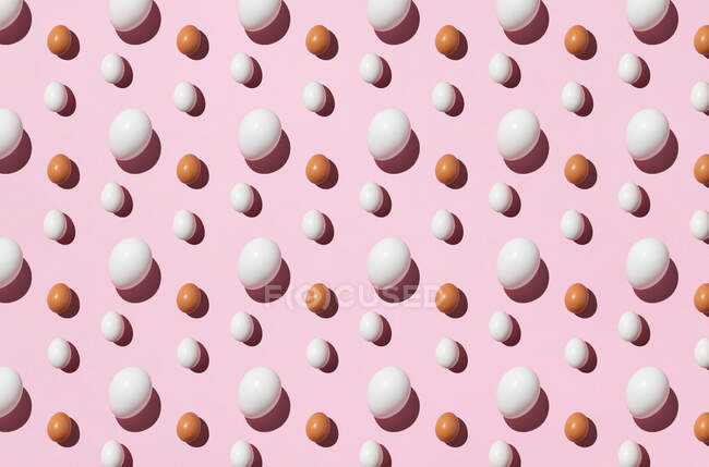 Seamless background of brown and white eggs on pink surface — Stock Photo