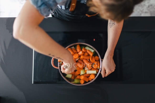 Woman cooking vegetable soup in kitchen — Stock Photo