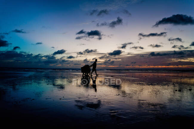 Silhouette einer Person, die am Strand spaziert — Stockfoto