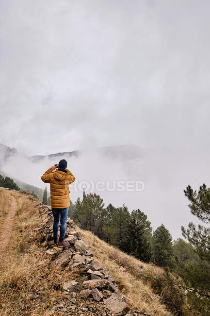 Неузнаваемый турист стоит на деревенском лугу и любуется видом — стоковое фото