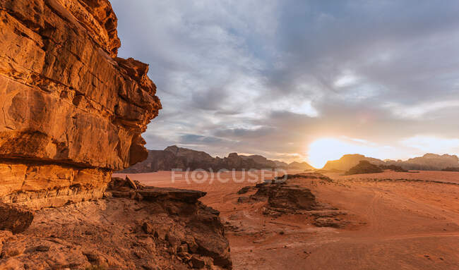 Puesta de sol vista del paisaje desierto de arena roja con montañas rocosas - foto de stock