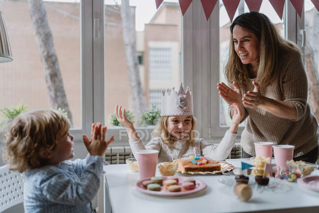 Позитивная мать играет с детьми во время празднования дня рождения — стоковое фото