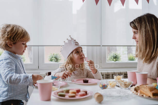 Woman sharing sweet chocolate dessert with flag on pink plate with kids at home — Stock Photo