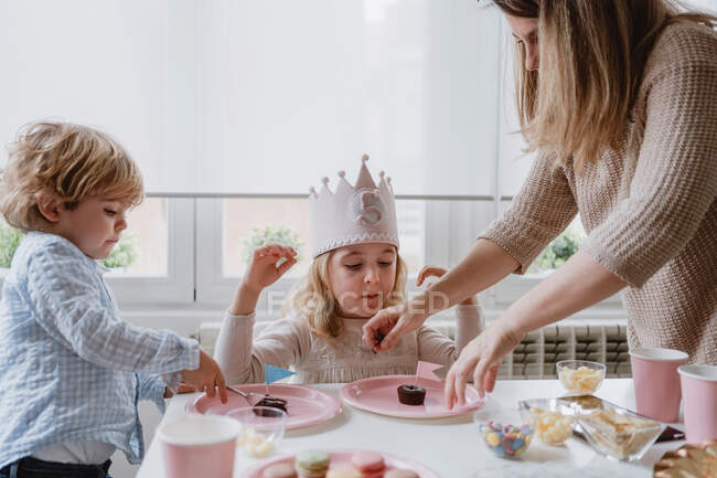 Donna che condivide dolce dessert al cioccolato con bandiera su piatto rosa con bambini a casa — Foto stock