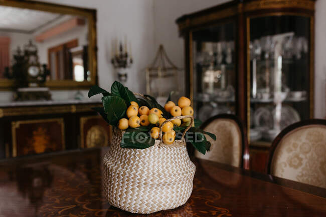 Panier en osier avec des fruits frais du loquat et des feuilles vertes à l'intérieur vintage — Photo de stock