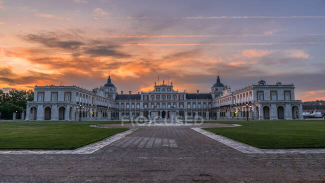 Facciata di palazzo medievale con vialetto e prati verdi sotto il cielo del tramonto — Foto stock