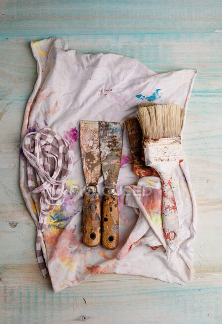 Dall'alto di pennelli squallidi e raschietti di metallo posti su tovagliolo colorato — Foto stock