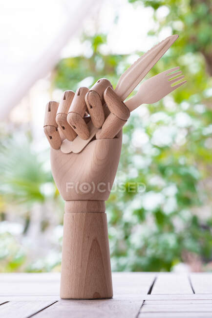 Mannequin créatif main avec fourchette jetable et couteau garni de brin de persil vert placé sur la table dans le jardin — Photo de stock