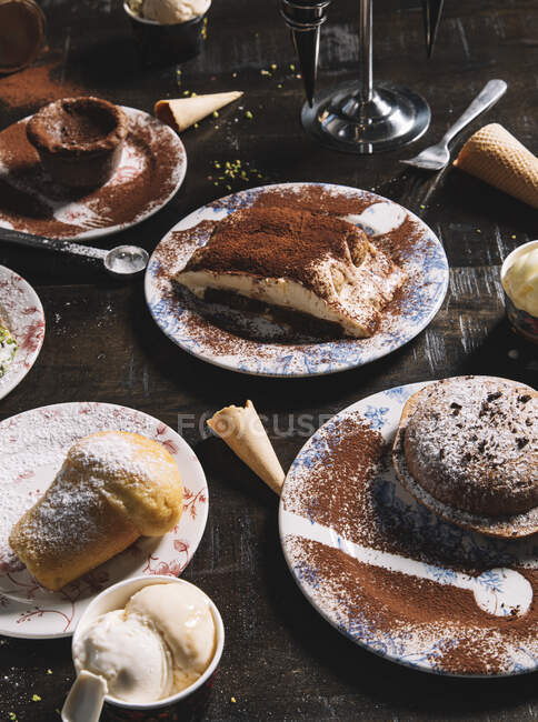 Alto ângulo de Tiramisu decorado com cacau em pó colocado na mesa com muffin e bolo de chocolate polvilhado com açúcar em pó — Fotografia de Stock