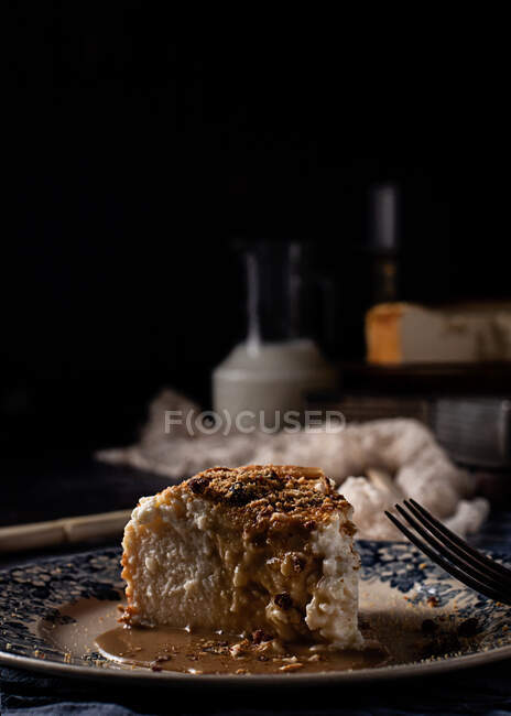 Pastel de queso con delicioso caramelo líquido en composición con ingredientes y utensilios entre delicadas telas sobre mesa de mármol azul - foto de stock